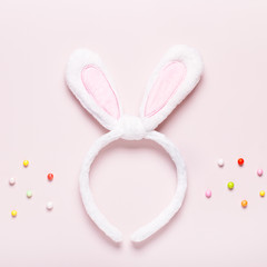 Funny cute bunny eggs and bunny rabbit ears for kids on pastel pink table top, Easter holiday concept. Easter decoration for kids flat lay, copy space