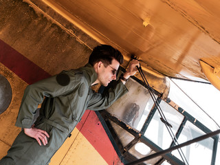 A handsome young pilot standing on the wing of a plane