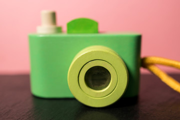 Cute toy retro camera in green on pink color background