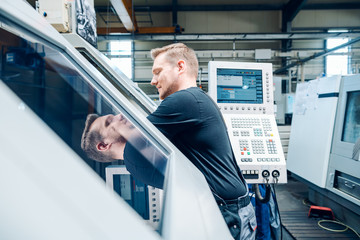 Worker resetting a cnc lathe machine in manufacturing factory