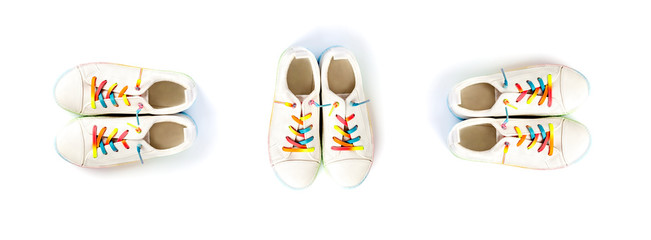 Three pairs white sneakers with rainbow laces for the child on a isolated backgroun. Top view.