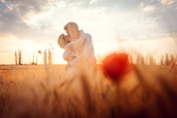 Wedding couple kissing in romantic setting on a wheat field