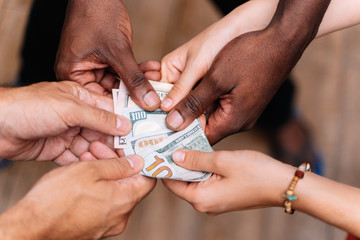 Hands of a group of people of different ethnicities holding a bill