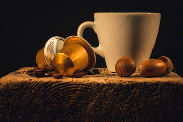 Cup of coffee in woodden background with coffee capusles ands coffee beans