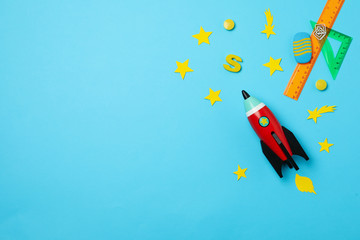 Bright toy rocket and school supplies on light blue background, flat lay. Space for text