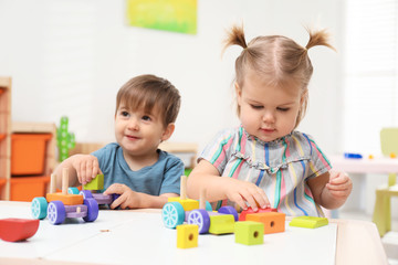 Fototapeta premium Little children playing with construction set at table