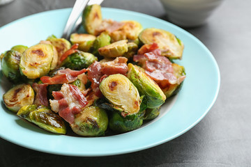 Delicious roasted Brussels sprouts with bacon served on black table, closeup