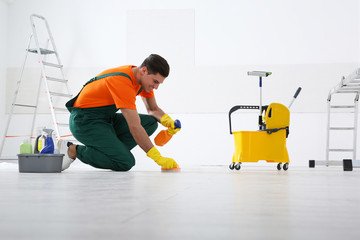 Professional janitor cleaning floor with brush and detergent after renovation