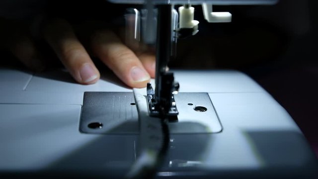 A tailor is sewing clothes with a sewing machine.