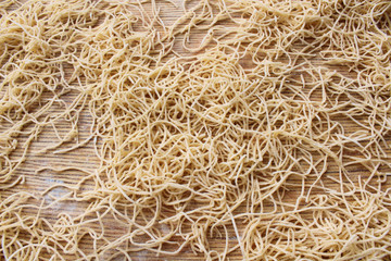 Dried thin noodles for soup on a wooden board. Close-up. Top view. Background. Texture.