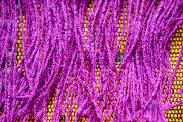 Purple Color Wool Detailed Threads Close Up on Dork Yellow Background 