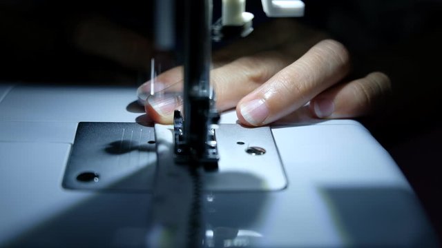 A tailor is sewing clothes with a sewing machine.