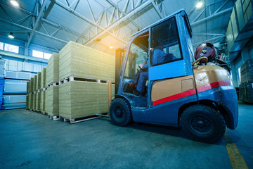 Worker driver of a forklift loader at warehouse of sandwich panels