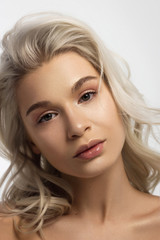 Naklejka premium Closeup portrait of a woman with developing straight hair. Sweet tender young girl blonde. Natural lipstick, transparent clean skin. Skin care natural cosmetics in the spa salon or cosmetology.