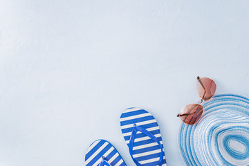 Flat lay composition with a summer hat and flip flops on a blue background