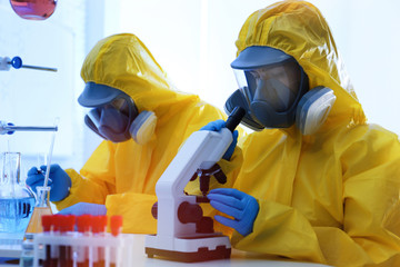 Scientists in chemical protective suits working at laboratory. Virus research
