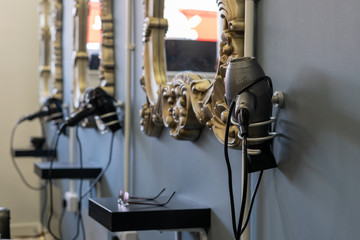 hair dryers on a stand in a salon with the hairdressers mirrors hanging on the walls