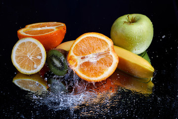 Fototapeta na wymiar Fruits with water splash on black background