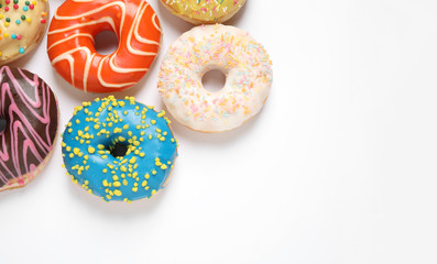 Delicious glazed donuts on white background, flat lay. Space for text