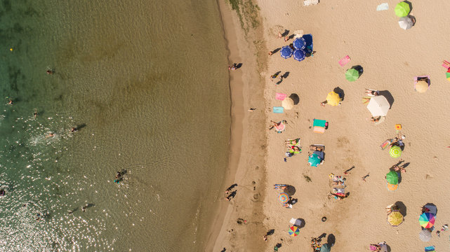 Top down view of beach with tourists and umbrellas with clear water. Tropical beach with colorful umbrellas. Holiday concept