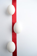 White egg wrapped around with red ribbon over white background
