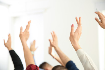 People raising hands to ask questions at business training indoors, closeup