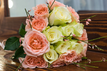  Elegant wedding bouquet of white and pink roses lying on the brown wooden table