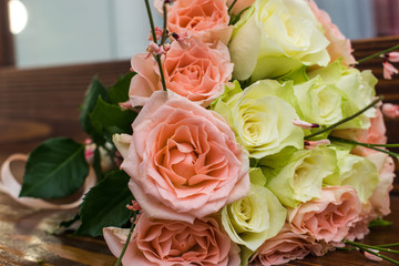 Elegant wedding bouquet of white and pink roses lying on the brown wooden table