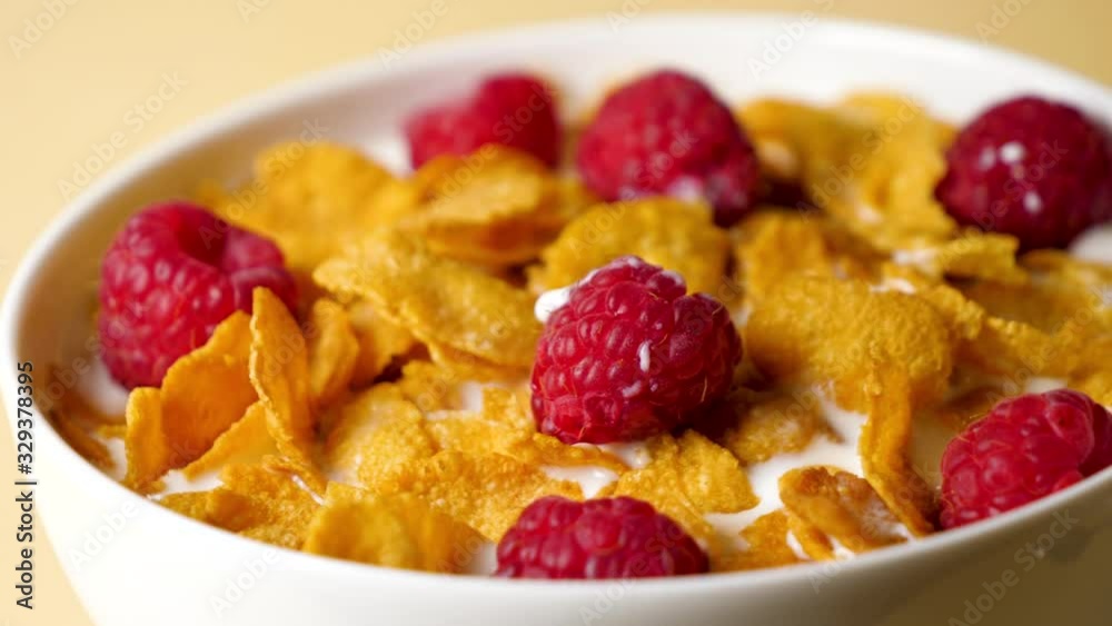 Sticker bowl of cornflakes with raspberries and milk, slow motion