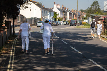 Fototapeta na wymiar 09/02/2019 Emsworth, Hampshire, UK Two elderly women walking down a street, one of the women is using a walking stick or walking aid