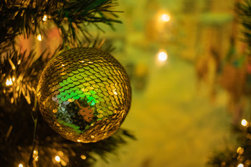 a gold bauble christmas decoration hanging on a tree