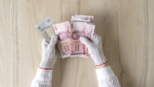Time lapse. Chinese female hand in protective from coronavirus (virus) gloves counting money of south-east Asia. Сhina yuan (CNY) Currency of Hong Kong, Indonesia, Malaysia, Thai, Singapore dollar.