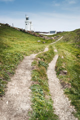 Fototapeta na wymiar a country track leading to a white lighthouse