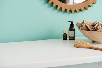 Hairbrush, bottles of eco body cream and oil, bowl with towels near mirror in bathroom, zero waste...
