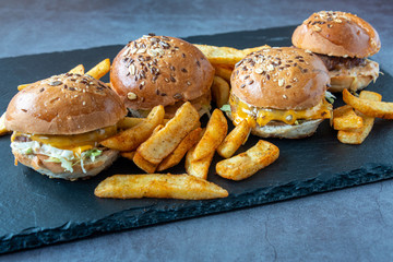 Hamburgers and French fries on dark textured background