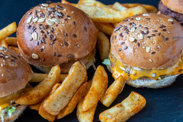 Hamburgers and French fries on dark textured background