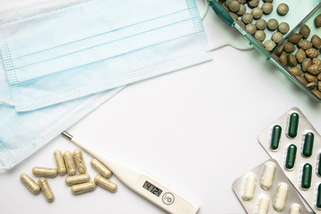 Flat lay protective medical face mask, digital thermometer with high temperature and scattered...