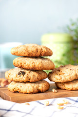 Homemade oat cookies with peanuts and raisins on the kitchen table, blue background, free space for text. Stack of oatmeal cookies close-up, copy space.