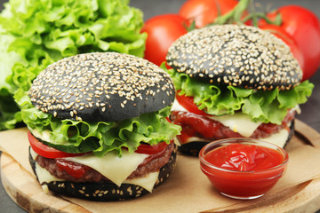 Two black burgers with vegetables and beef meat	