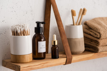 Selective focus of hygiene and cosmetic products with towels on shelf in bathroom, zero waste...