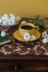 Cup of coffee, cookies, little book and flowers on brown marble table