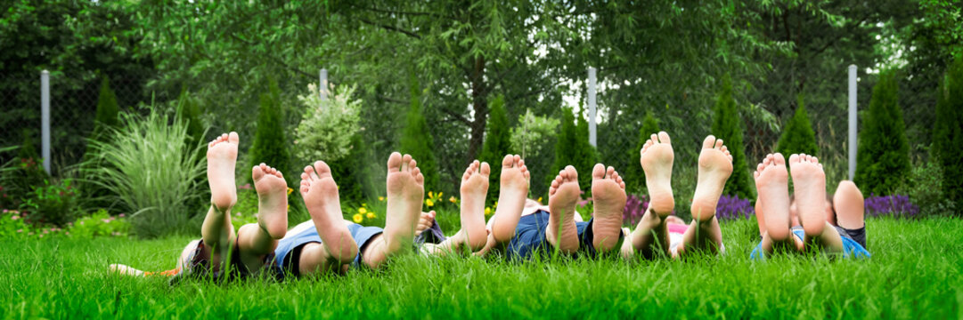 Family relaxing on green grass, barefoot laying down and looking into the sky