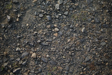 Detail of surface texture with small pebble rock on dirty ground.