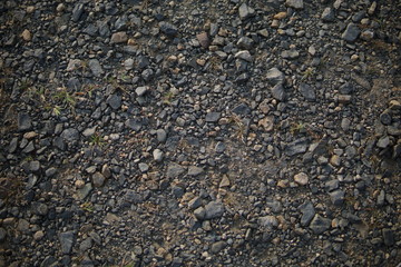 Detail of surface texture with small pebble rock on dirty ground.