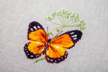 Cross-stitch butterfly with pink wings.