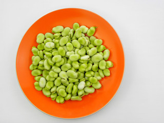 green beans in an orange plate on a white background