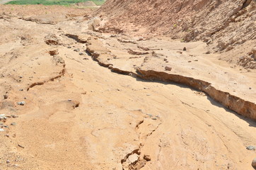 Background of yellow sand with small stones after rain. Soil erosion after heavy rainfall and precipitation. Texture of scattered sand fine gravel