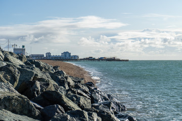 South parade pier in Southsea, Hampshire with waves hitting rocks in the foreground