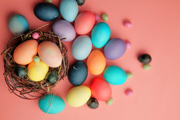 Multicolored eggs and lollipops in a nest on a pink background, Easter.