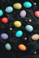 Colorful eggs and lollipops on a black background, Easter.